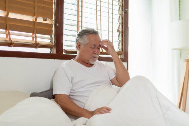 Asyalı yaşlı bir adam beyaz saçlar baş ağrısı ve migren o kadar acı ve hastalık ki, stresli yaşlı adam evde tek başına oturuyor, mutsuz yaşlı adam kafasına dokunuyor ciddi ve denenmiş, mutsuz yaşlı konsept