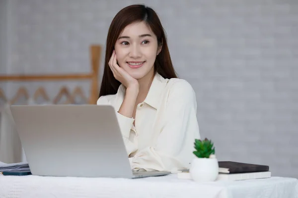コンピュータのラップトップと笑顔で自宅で働く幸せなアジアの若いビジネス女性 彼女のビジネススタートアップの成長価値のためのビジネスプランの笑顔と陽気について考える若い女性の起業家 — ストック写真