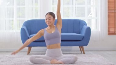 Spor elbiseli Asyalı bir kadının evde yoga yaparak nefes almak ve meditasyon yapmak için kas germesi, yoga yapan sağlıklı bir kadının kendini çok rahat ve rahat hissetmesi, Sağlık Yogası Sağlık Konsepti