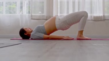 Hamile Asyalı genç kadın yoga ile meditasyon yapıyor. Yarı Köprü pozu veriyor. Yoga yapıyor. Genç sağlıklı hamile bir kadının meditasyonu.