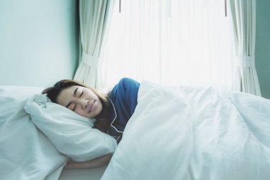 Güzel, çekici, Asyalı bir kadın sabahları yatakta tatlı rüyalar görür. Sağlık sigortası kavramı.