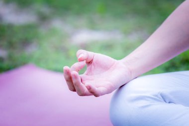 Yoga nilüferini pratik yaparken elinizi kapatın. Yeşil çimenlikte meditasyon için poz verin. Egzersiz sonrası kendinizi rahat ve rahat hissedin.