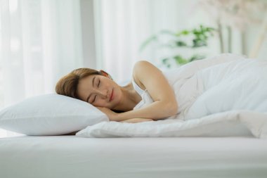 Güzel, çekici, Asyalı kadın uyuyor ve tatlı rüyalar, rahat bir yatak odasında yatakta uzanıyor, rahat ve rahat uyuyor, uyku ve dinlenme sağlık sigortası kavramı.