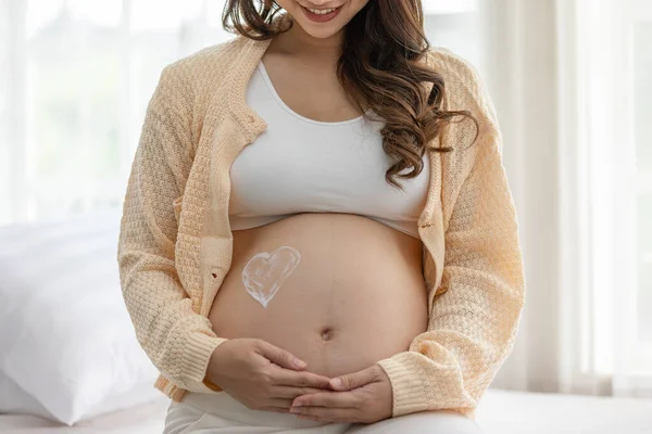 Glückliche Schwangere Bett Sitzend Und Streichelnd Creme Auf Dicken Bauch — Stockfoto