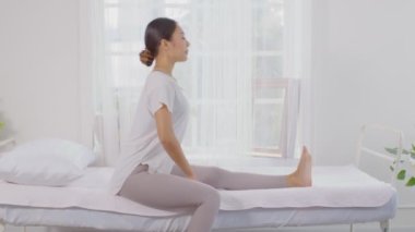 Sağlıklı, Asyalı genç bir kadın yatakta soluklanır ve yoga yapmadan önce esner, genç sağlıklı bir kadın beyaz rahat evinde kaslarını ısıtır ve rahatlar, Yoga Sağlık Konsepti