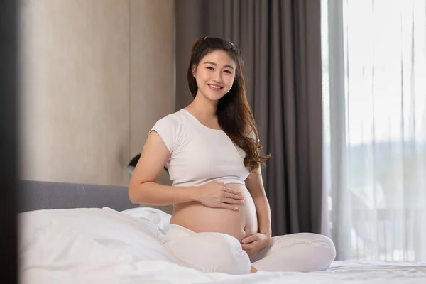 Happy Pregnant Asian Woman Sitter Sängen Håller Och Smeker Sin — Stockfoto