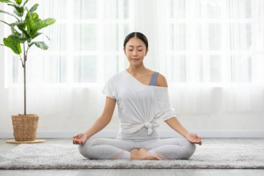 Sağlığın huzuru Asyalı genç kadın halının üzerinde yoga nilüferiyle soluk alıp veriyor, Yoga yapıyor sağlıklı genç bir kadının meditasyonu, beyaz rahat evinde dinleniyor ve rahat, Yoga sağlık egzersizi yapıyor.