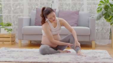 Hamile bir kadın, baldırına dokunup masaj yapıyor. Çok acıyor ve kramp giriyor. Kas kaslarının stresi ve hamilelik konsepti yüzünden bacağına kramp giren bir kadın. 