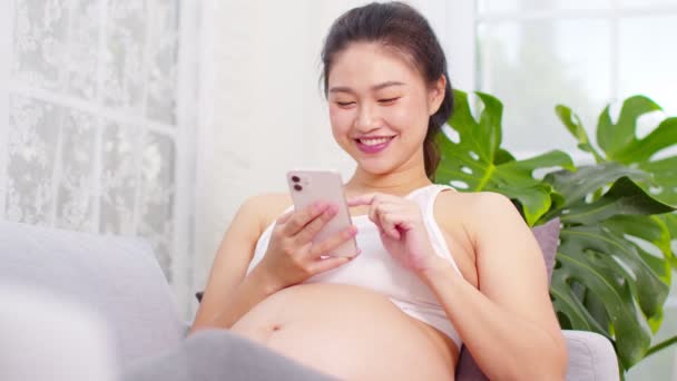 Lycklig Gravid Asiatisk Kvinna Använder Mobiltelefon För Att Titta Video — Stockvideo