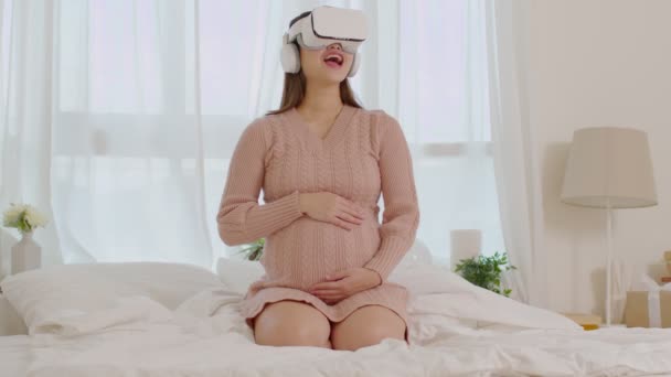 新生児の世話をするための練習のチュートリアルのための仮想現実の眼鏡を使用して幸せな妊婦 アジア妊娠中の女性は 仮想現実やVrを使用してゴーグルは自宅でお楽しみください 妊娠技術 — ストック動画