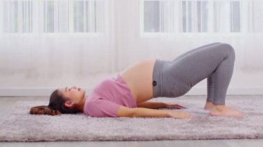 Hamile Asyalı genç kadın yoga ile meditasyon yapıyor. Yarı Köprü pozu veriyor. Yoga yapıyor. Genç sağlıklı hamile bir kadının meditasyonu.