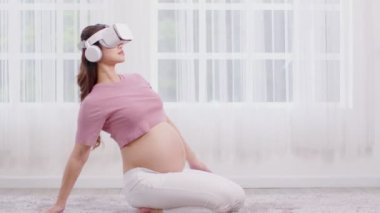 Mutlu Asyalı hamile kadın sanal gerçeklik gözlüklerini kullanarak yoga dersi için Ustrasana pozu veya yoga devesi pozu vererek meditasyon gülümsemesi ile evde rahatlayın. Hamilelik teknolojisi kavramı