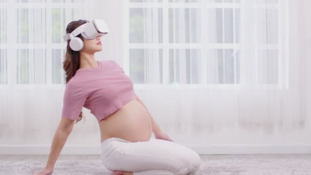 幸せなアジア妊娠中の女性の練習のための仮想現実の眼鏡を使用してヨガオンラインクラスUstrasanaポーズまたはヨガラクダのポーズ自宅で大きな腹でリラックスして笑顔瞑想にポーズ 妊娠技術の概念 — ストック動画