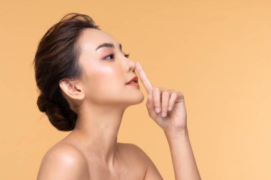 Güzel Asyalı kadın burun teması yapıyor temiz ve taze tenli mutlu ve neşeli bej, estetik cerrahi burun, güzellik kozmetik ve kaplıca yüz bakımı konsepti üzerinde olumlu duygusal