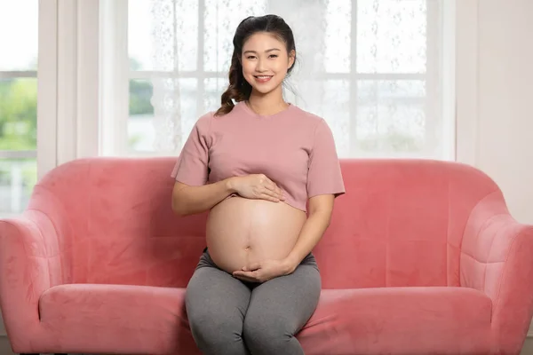 Glückliche Schwangere Sitzt Auf Rosa Couch Hält Und Streichelt Ihren — Stockfoto