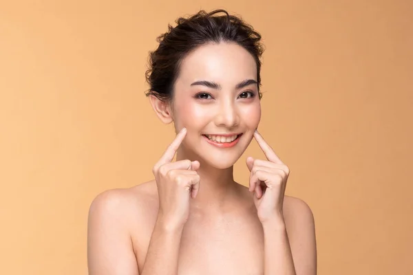美丽的亚洲年轻女子 用清爽的肌肤触摸着柔软的面颊 快乐而快乐 有着积极向上的情绪 被米色背景 美容美发和面部治疗理念所隔离 — 图库照片
