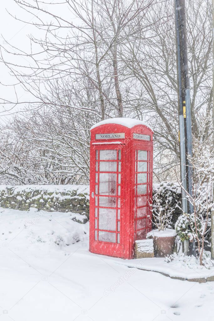 A traditional red British telephone box in the snow in winter