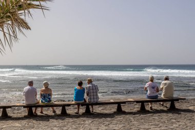 Tenerlife 'da bir bankta oturan insanlar