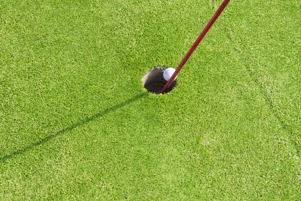 Mini golf ball going in hole — Stock Photo, Image