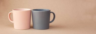 Kahve için iki fincan pembe ve gri, bej arka planda duruyor. Mesajlaşmak için bir yer. Pankart. Kahve günü. Sevgililer Günü. Kapalı bardaklar. Kahveli minimalizm. Kahvaltı.