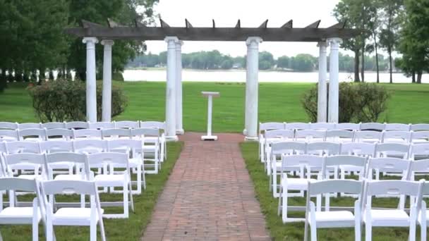 为夏天的婚礼登记设计了漂亮的场地 在绿树成荫的草地上 在地平线上的池塘上 用白色的色调进行登记 — 图库视频影像