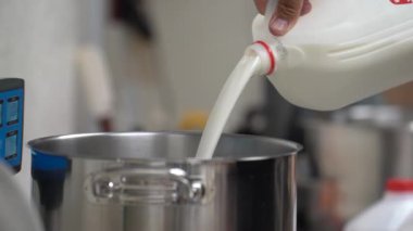 Yemek pişirme alanı. Mutfak masası. Kalın beyaz krema ve süt tencereye dökülür. İnce bir damla. Yemek pişirmek. Tatlı. Tarifin inceliği. Ev yapımı tatlılar..