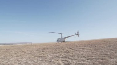 Ticari uçuşlar için küçük beyaz bir helikopter. Mavi gökyüzüne karşı tek motorlu bir helikopter kalkıyor..