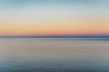 Gün batımının kırmızı, turuncu ve mavi renkleri ile deniz ufku