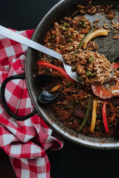 Tipik İspanyol paella biber ve bezelye ile, büyük bir kaşıkla servis edilir.
