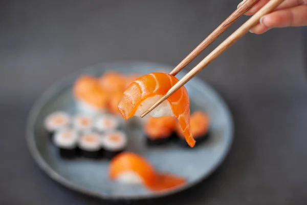 Sushi nigiri japonais traditionnel au saumon placé entre les baguettes Image En Vente