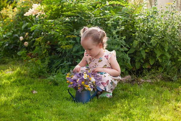 Petite fille cueillette des fleurs sauvages avec arrosoir dans le jardin — Photo