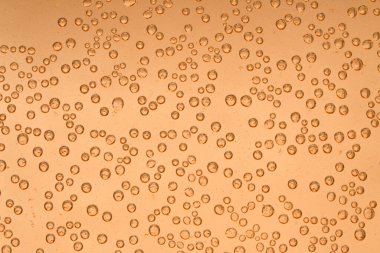 Parlak altın tanecikli cam üzerindeki hava kabarcıkları ılık sarı arkaplan