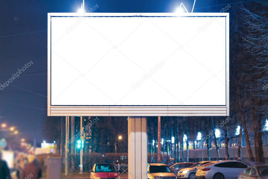 Big billboard standing in the city. at night lit by lamps.