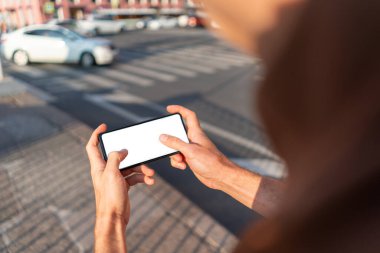 Adam akıllı telefonu iki eliyle tutuyor.