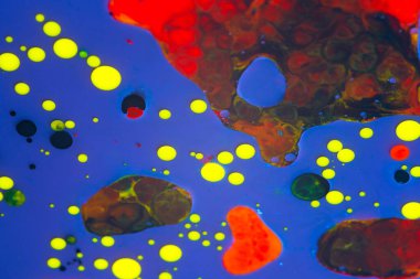 Su yüzeyindeki bir boya damlasının soyut arkaplanı. mavi kırmızı sarı renk damlaları