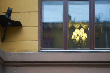 Pencerenin yanındaki duvarda bir kedi heykeli. St. Petersburg manzarası