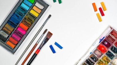 Beyaz kağıda, püsküllere, kalemlere, suluboya resimlere, pastel sanat malzemelerine yassılaştırılmış sanat materyalleri.