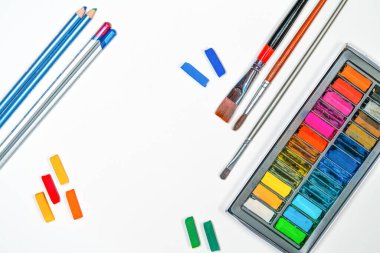 Beyaz kağıda, püsküllere, kalemlere, pastel sanat malzemelerine yassılaştırılmış sanat materyalleri.
