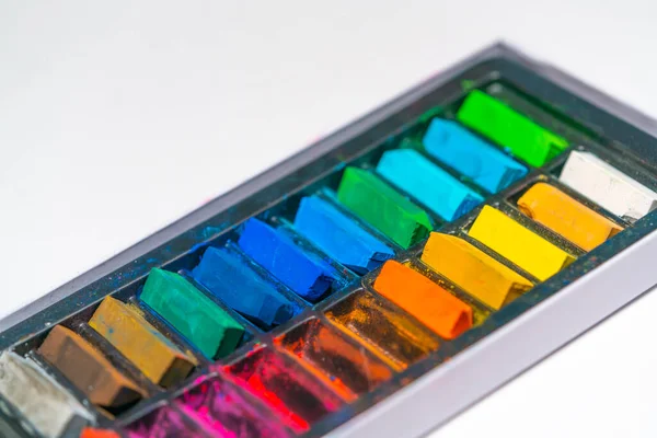 Pastel sanat malzemeleri, beyaz kağıt arka plandaki bir kutuda farklı renklerde boya kalemleri.
