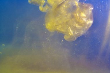 Su altının içindeki mürekkep boyası patlaması suda parlıyor, parçacıklar parlıyor.