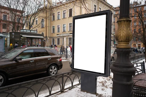 Vertical city billboard with white field MOCKUP. In the city center in the afternoon with snow in the winter.outdoor advertising ad
