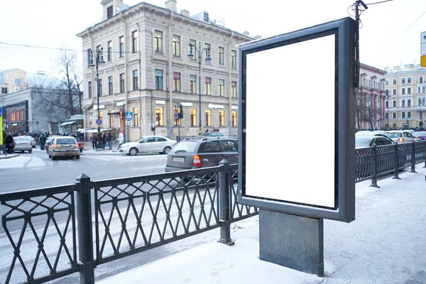 Vertical city billboard with white field MOCKUP. In the city center in the afternoon with snow in the winter outdoor advertising ad.