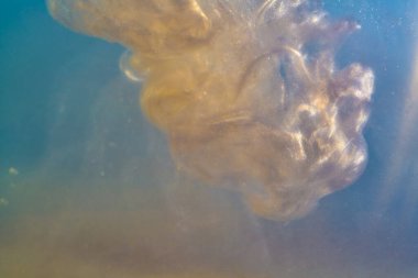 Su altının içindeki mürekkep boyası patlaması suda parlıyor, parçacıklar parlıyor.