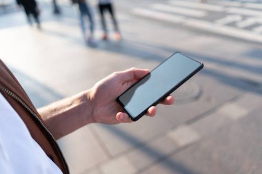 Telefon çerçevesi olmayan bir adamın elinde. Sokakta.