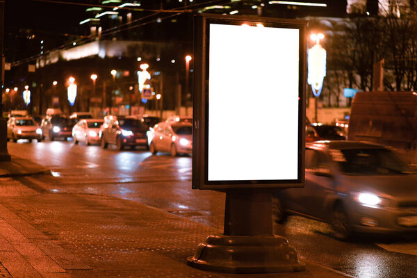 glowing at night billboard advertising table, night city road with cars Layout for placement of outdoor advertising design.