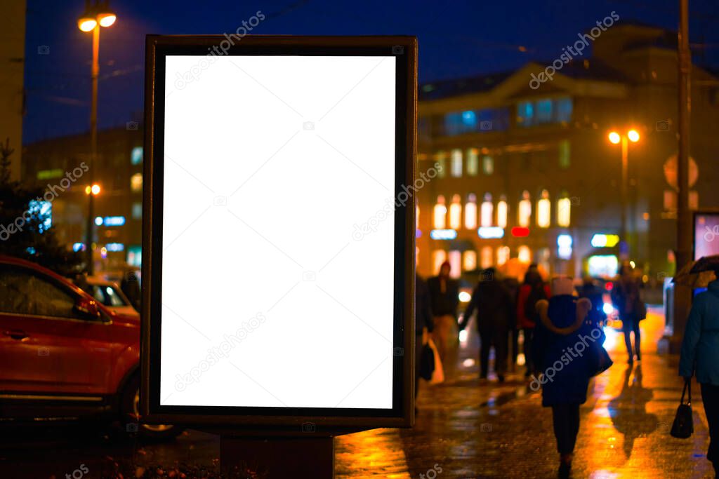 the billboard ad night city, shines in the night city. mockup with a white field for advertising. rainy evening, wet weather and road