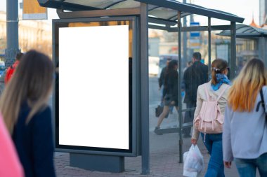 Şehirde dikey reklam panosu ışık kutusu var. MOCKUP reklamını arka plandaki insanlarla birlikte otobüs durağına yerleştirmek için.