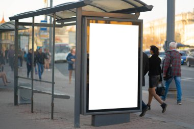 Otobüs durağındaki reklam panosunda dikey reklam panosu. MOCKUP reklamını arka plandaki insanlarla birlikte dış mekan reklamcılığına yerleştirmek için