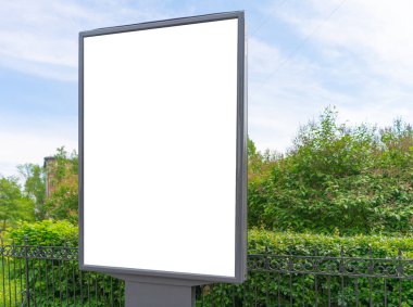 Yeşil bitki çalıları ve mavi gökyüzünün arka planına karşı dikey reklam panosu. Reklamcılık için bir yeri var.