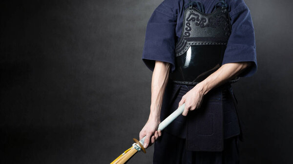 Kendo fighter in armor practicing with bamboo sword. Special bamboo sword and sports uniform. Photo of torso with hands.